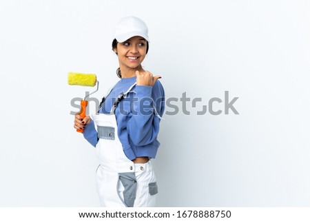 Painter woman over isolated white background pointing to the side to present a product