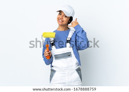 Painter woman over isolated white background making phone gesture and pointing front