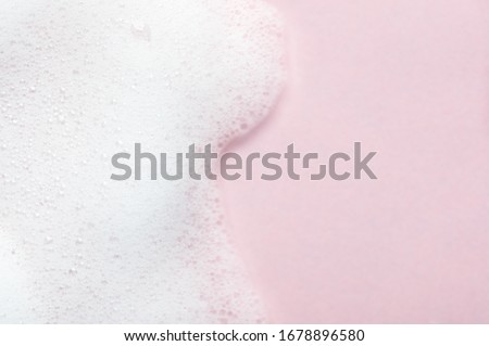 Foaming liquid on pink backdrop. Cosmetics foam background with copy space in right side. Cosmetic product sample of mousse, shampoo or soap. Skincare, cosmetology and beauty concept Royalty-Free Stock Photo #1678896580