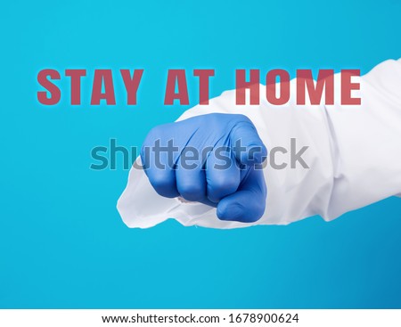 doctor’s hand in a blue sterile glove shows with an index gesture in front, request or appeal to pay attention to stay at home during quarantine