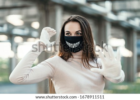 Young girl in funny medical mask and gloves shows stop sign