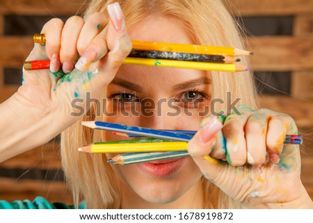 Concept: the world is colorful and wonderful. Humorous photo of great artist. Portrait of beautiful young woman with colored pencils.