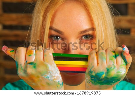 Portrait of beautiful blonde young woman with colored pencils as symbol of art and creativity.