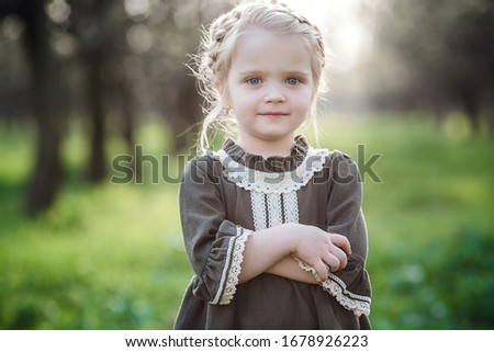 small cute girl in dress in blossom garden. Cute baby girl 3-4 year old holding flowers over nature background. Spring portrait. Aromatic blossom and retro vintage concept.