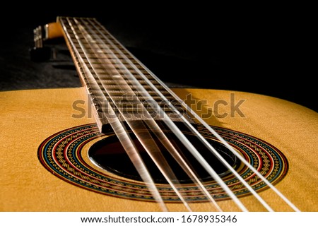 Classical guitar with vibrating strings on a black background Royalty-Free Stock Photo #1678935346