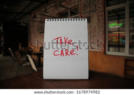 Take care text written by hand on a paper on the empty street cafe table