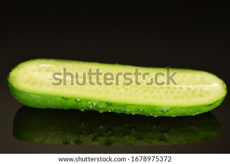 One half green organic ripe juicy cucumber, close-up, on a black background.