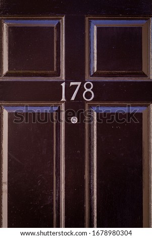 House number 178 on a black wooden front door