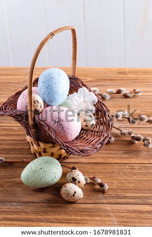 Congratulation Easter card from basket with handmade painted chicken and quail eggs on a wooden background.