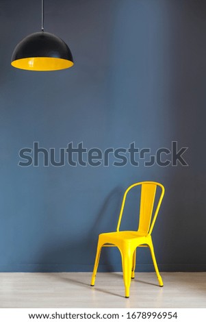 Living room wall mock up with dark grey wall and bold yellow chair and lamp. Illuminating Yellow and Ultimate Gray, colors of the year 2021