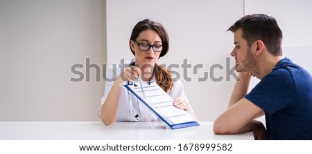 Male Patient Looking At Test Results Held By Doctor
