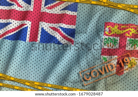 Fiji flag and Covid-19 biohazard symbol with quarantine orange tape and stamp. Coronavirus or 2019-nCov virus concept