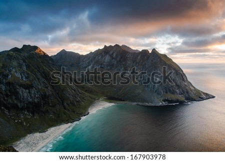 Spectacular sunset view to rugged mountain peaks above Kvalvika - famous surfing beach at Lofoten islands, Norway