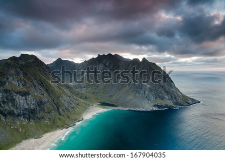 Dramatic view to rugged mountain peaks above Kvalvika - famous surfing beach at Lofoten islands, Norway