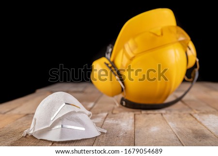 Workwear and protective mask on a wooden table. Protective accessories for the production worker. Dark background.
