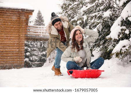 Couple having fun and sledding on snow. Winter vacation