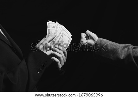 Deal. Arm transfer of money. Currency transfer on black background. Black and white photo. Dollars transfer  