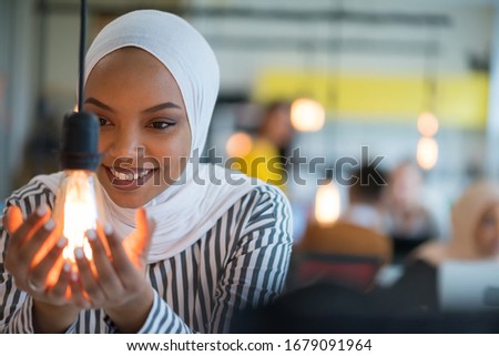 Beautiful african muslim woman holds modern lamp bulb with smiling happy expression, idea concept with selective focus. Royalty-Free Stock Photo #1679091964