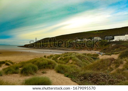 Grassy sand dunes behind saunton beach in north devon waving in the rough autumn winds. Royalty-Free Stock Photo #1679095570