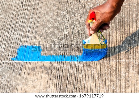 The painter is painting the traffic sign on the concrete road
