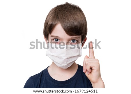 Portrait of kid with face mask pointing finger up, isolated on white background
