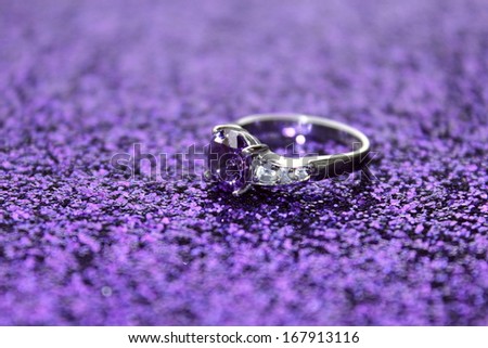 A pretty amethyst ring on a purple sparkling surface Royalty-Free Stock Photo #167913116
