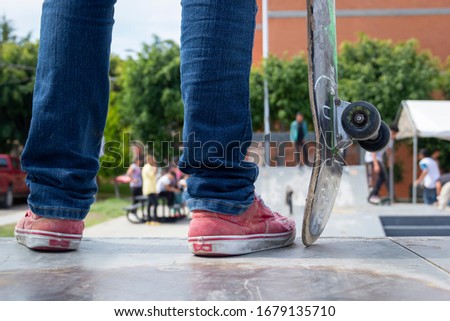 Young man in skate park standing on a ramp with his skateboard. Extreme Skateboarding Practice Sports Concept