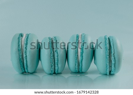 Four blue pastel french macaroons on a blue background. Still life with copy space.