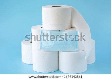  Toilet paper stacked rolls, medicine mask on a blue background. Items that buiyng in panic. Toilet paper crisis due to coronavirus COVID-19 quarantine. Copy space