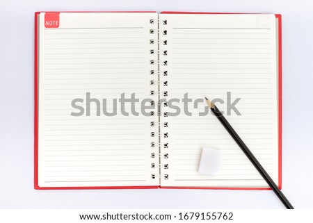 The top picture of the notepad has a straight line,the red cover is open,there is a black pencil and an eraser placed on the notebook. For recording work and personal stories.Isolated white background