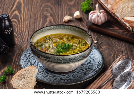 Fragrant chicken soup with egg with garlic and herbs on a wooden table