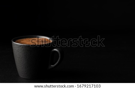 A cup of espresso with foam. Black stone background. Copy space for text. Close-up, shallow depth of field. Morning hours waiting for coffee.