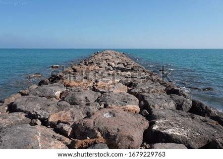 A path with big stones in the clear blue sea