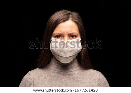 a woman in a mask , a tense, restless look at the camera. concern about a coronavirus infection , an attempt at protection. Studio portrait close -up