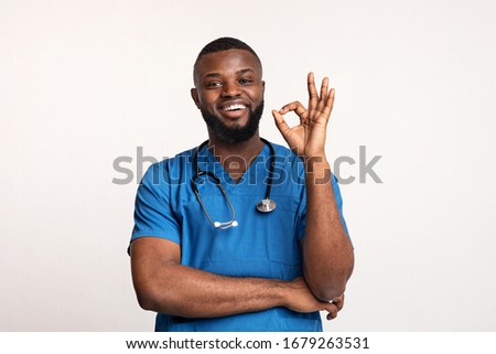 African young doctor recommending his modern clinic over white background, showing okay gesture