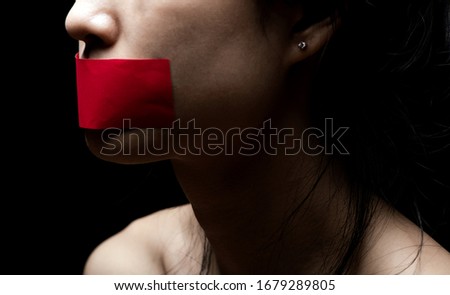 Concept on the topic of freedom of speech, censorship, freedom of press. International Human Right day: the girl's face is sealed her mouth with red paper