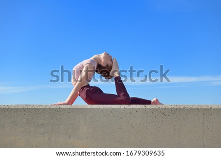 Portrait of a fit woman who practices yoga outdoors. Woman practicing asanas on a sunny day with a blue sky in the background