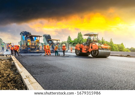 Construction site is laying new asphalt road pavement,road construction workers and road construction machinery scene.highway construction site landscape. Royalty-Free Stock Photo #1679315986