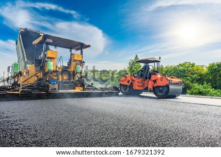 Construction site is laying new asphalt road pavement,road construction workers and road construction machinery scene.highway construction site landscape. Royalty-Free Stock Photo #1679321392