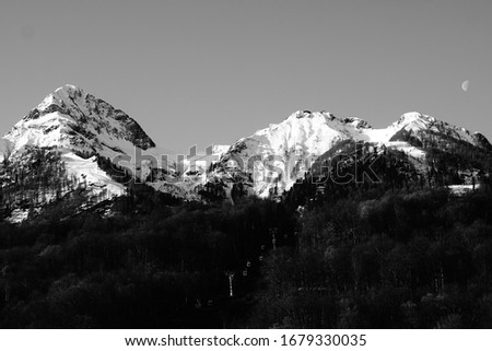 
Mountains covered with snow, a lift passes between the mountains. black and white picture.                 