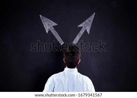 Businessman looking to a chalkboard with to arrows trying to decide one solution