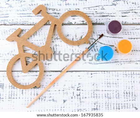 Decorative bicycle with brush and paints on wooden background