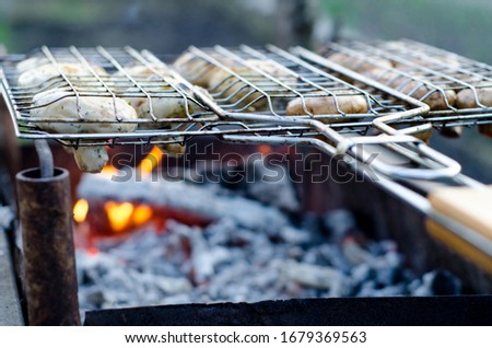 Delicious juicy champignon white mushrooms in soy sauce and mayonnaise are fried in a grid on the coals grill or BBQ steam, on a homemade grill, closeup