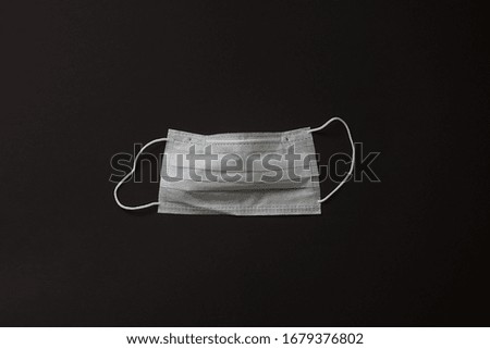 Surgical mask for personal protection isolated on black background. Typical three-layer surgical mask for covering the mouth and nose. The procedure with a bacterial mask. Protection concept.