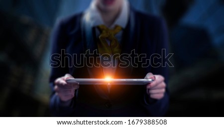 A computer tablet in the hands of a man on a dark background with neon light, a flash of light, magic