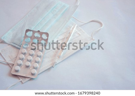 medical mask on white background, top view, health care, tablets in a blister, thermometer
