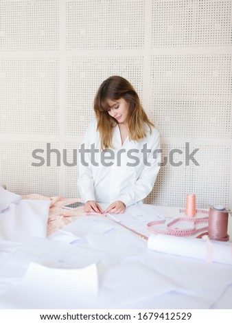 Side view of a young female fashion designer working on her designs in the studio. Fashion Designer Sketch Drawing Costume Concept. work space