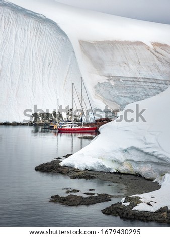 two yachts and ship wreck between snow hills in Antarctica