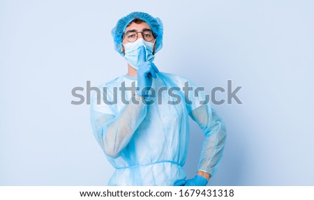 young man looking serious and cross with finger pressed to lips demanding silence or quiet, keeping a secret. coronavirus concept