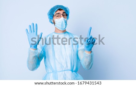 young man smiling and looking friendly, showing number six or sixth with hand forward, counting down. coronavirus concept